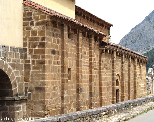 Muro de la nave lateral meridional de la colegiata de San Pedro de Teverga con la puerta de ingreso, los contrafuertes y la colección de canecillos