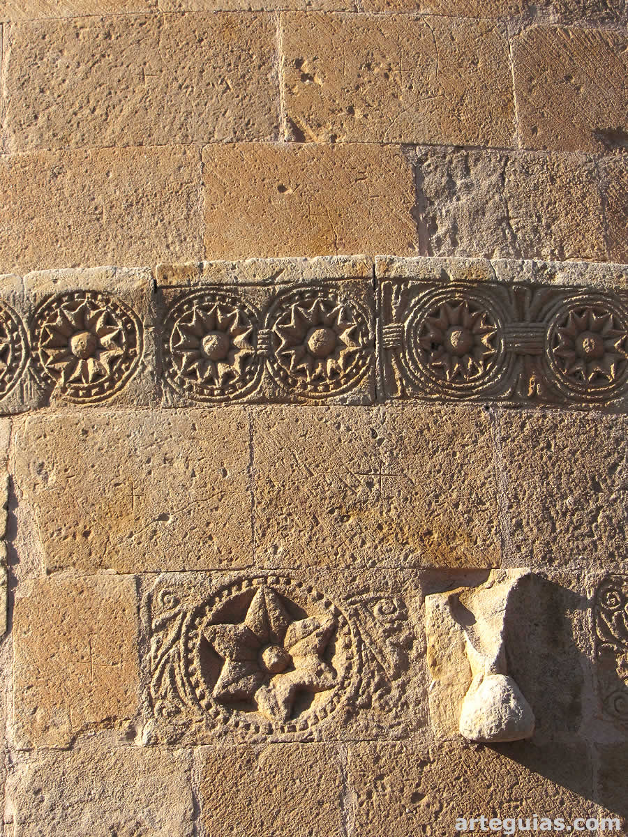 Muro absidal de la iglesia con dos registros de relieves románicos